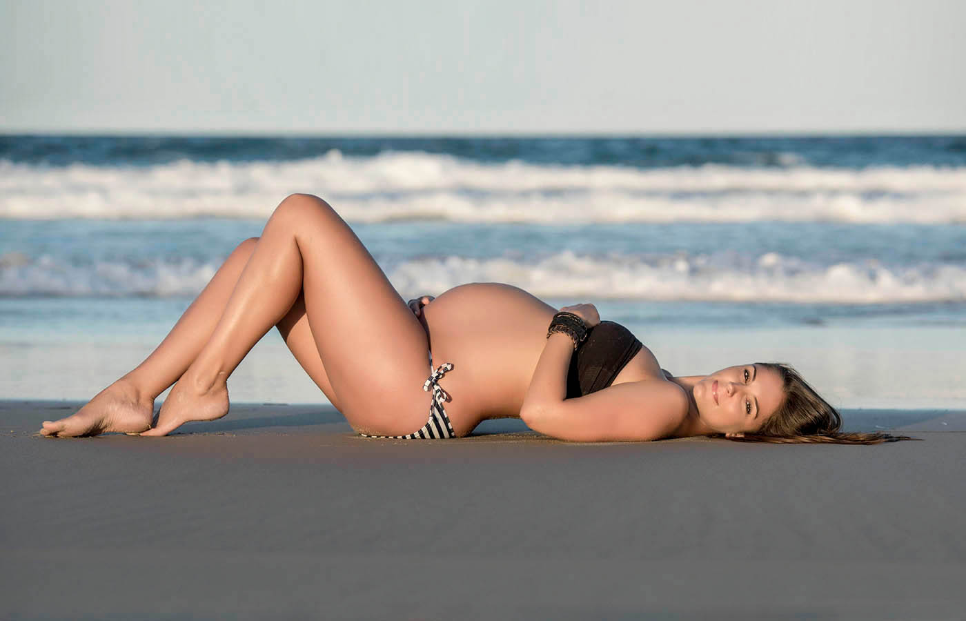 A maternity photograph of a woman on a beach in Brisbane by Jessica Loren.