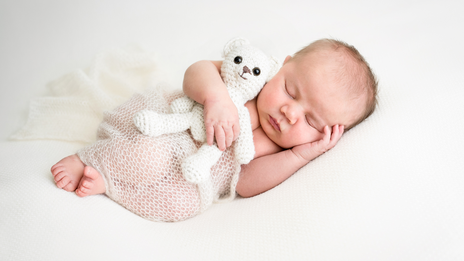 A photograph of a sleeping newborn baby cuddling a soft toy taken by Jessica Loren at her studio in Brisbane.